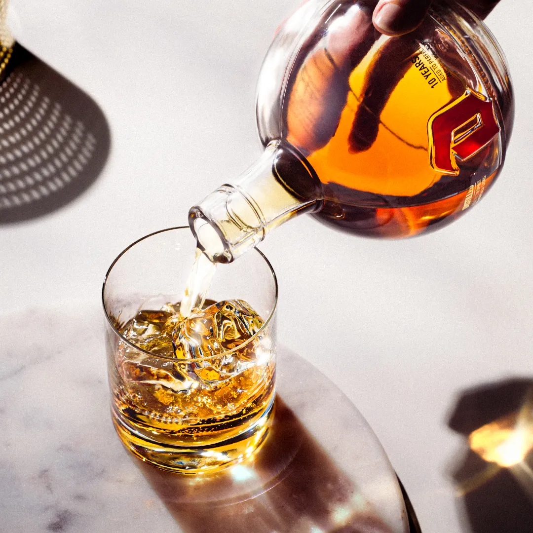 One hand pours a glass of Duvel Distilled.