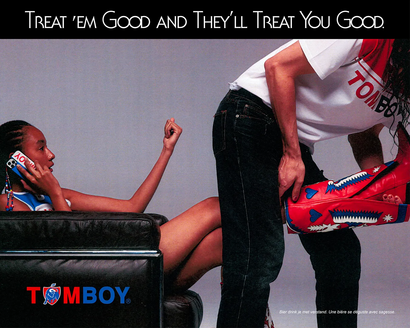 Poster for the Tomboy x Jupiler campaign showing a young woman sitting on the telephone, a man removing her boot.