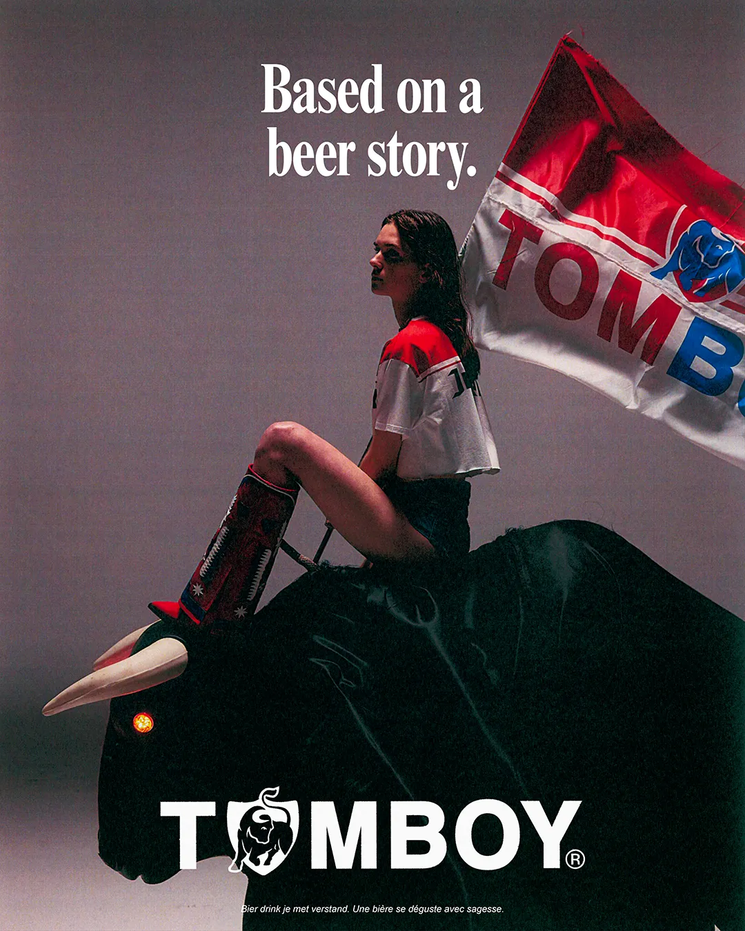 Poster for the Tomboy x Jupiler campaign showing a young woman sitting on a mechanical bull.