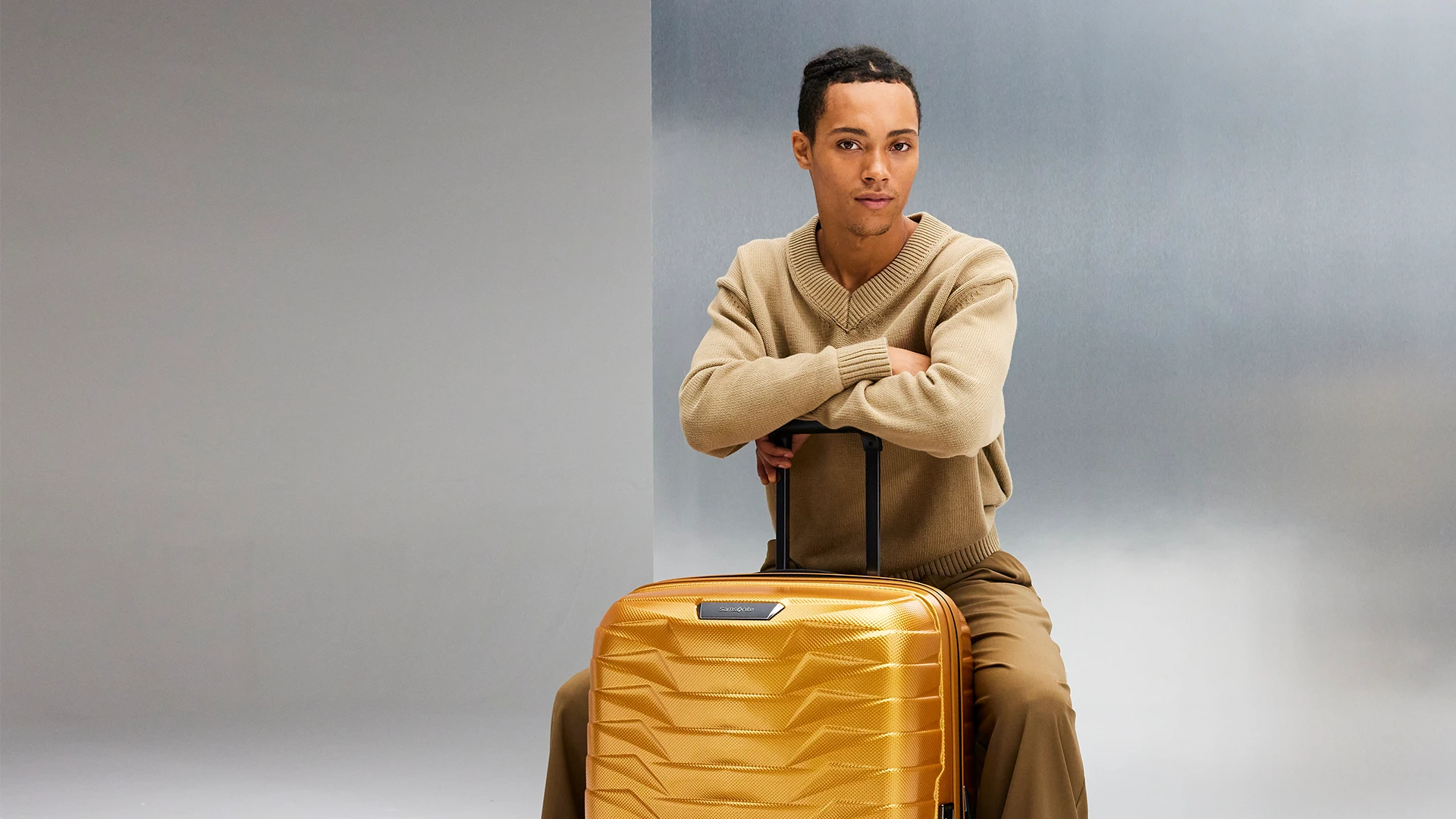 A young man with a Samsonite Proxis suitcase in a studio.