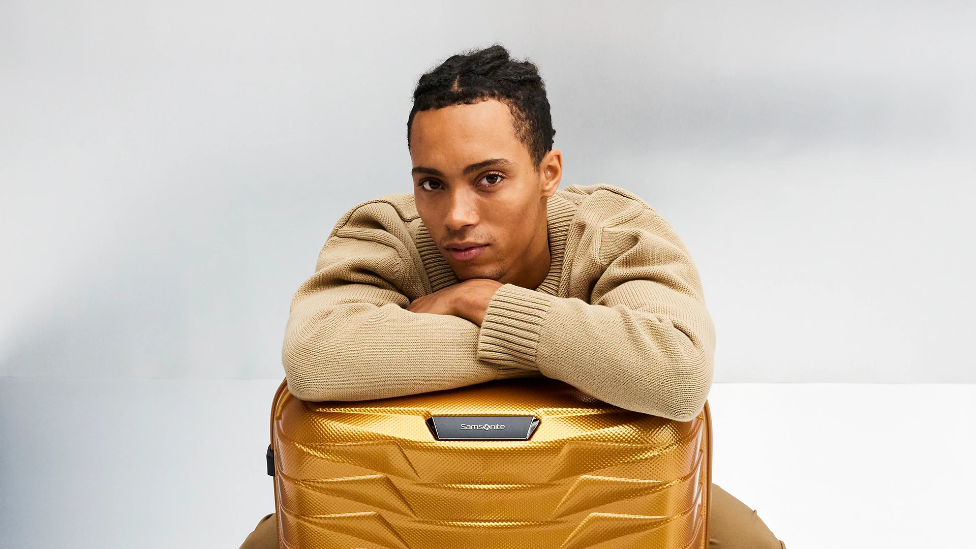 A young man with a Samsonite Proxis suitcase in a studio.