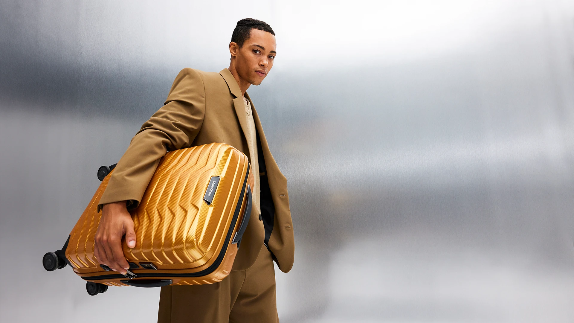 A young man with a Samsonite Proxis suitcase in a studio.